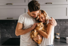 brunette man looking at his cat and embracing wife indoor portrait of happy family posing with pet scaled 1 1