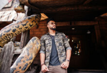 awesome beautiful tall ararbian beard macho man in glasses and military jacket posed outdoor against snake python scaled 1