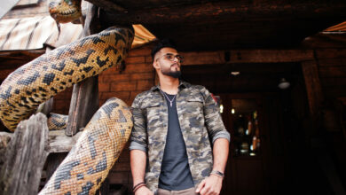 awesome beautiful tall ararbian beard macho man in glasses and military jacket posed outdoor against snake python scaled 1