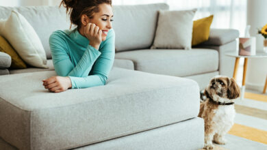 mulher feliz deitada no sofa enquanto relaxa com seu cachorro em casa scaled 1